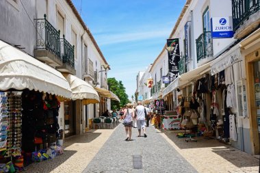 Dükkan ve kaldırım kafeleri R 25 de Abril alışveriş caddesi Lagos, Algarve, Portekiz tarafından geçen turistler ile eski şehir boyunca.