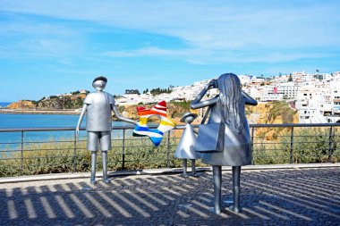 Bir kadının kocası ve kızı bir fotoğraf Miradouro adlı çekici metal heykel yapmak Pau da Bandeira kasaba ve arka, Albufeira, Portekiz için okyanus manzaralı,.