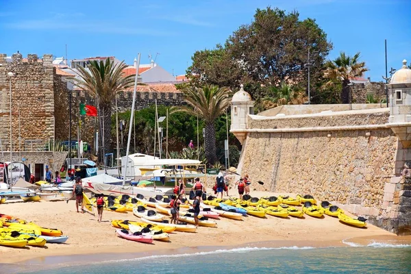 Pohled z Ponta da Bandeira Fort s kanoí na pláži v popředí a turisty těší nastavení, Lagos, Algarve, Portugalsko,. — Stock fotografie