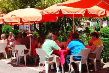 Turistler Orange Square, Marbella, İspanya 'da bir kaldırım kafesinde dinleniyorlar..