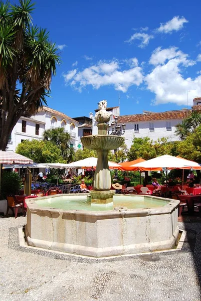 Fuente de piedra con turistas relajándose en los cafés de calle en Orange Square, Marbella, España . —  Fotos de Stock