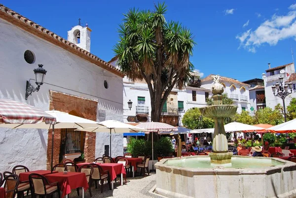 Fuente de piedra con turistas relajándose en los cafés de calle en Orange Square, Marbella, España . —  Fotos de Stock