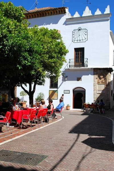 Turistas relajándose en una cafetería en Orange Square con la oficina de información turística en la parte trasera, Marbella, España . — Foto de Stock