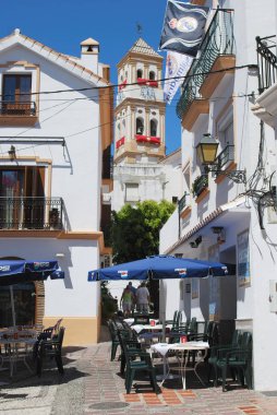 Santa Maria kilisesi saat kulesi arka tarafta Marbella, İspanya 'da bulunan eski şehirdeki Pavement Kafe..