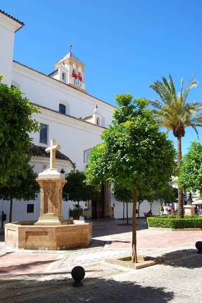 Stenen fontein op het kerkplein met de Santa Maria kerk aan de achterkant, Marbella, Spanje. — Stockfoto