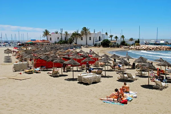 Туристы отдыхают на пляже Дайтона с пристани для яхт в задней части, Марбелья, Испания . — стоковое фото