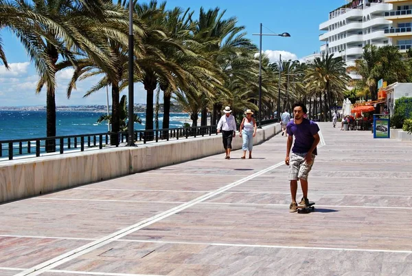 Turistas a lo largo del paseo marítimo junto a la playa de Daitona con vistas a lo largo de la costa, Marbella, España . — Foto de Stock