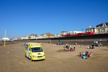 Turistler plajda ön planda dondurma kamyonuyla dinleniyor, Burnham-on-Sea, Uk.