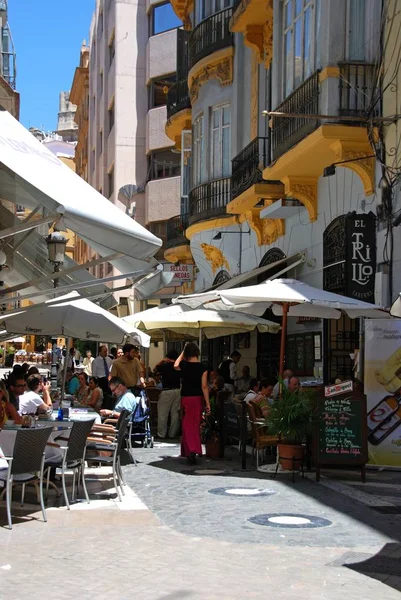 Lidé relaxaci v kavárnách chodníku v boční ulici z Calle Marques de Larios v centru města, Malaga, Španělsko. — Stock fotografie