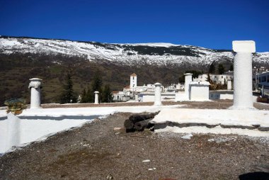 View over village rooftops towards the snow capped Sierra Nevada mountains, Capileira, Las Alpujarras, Granada Province, Andalucia, Spain, Western Europe. clipart