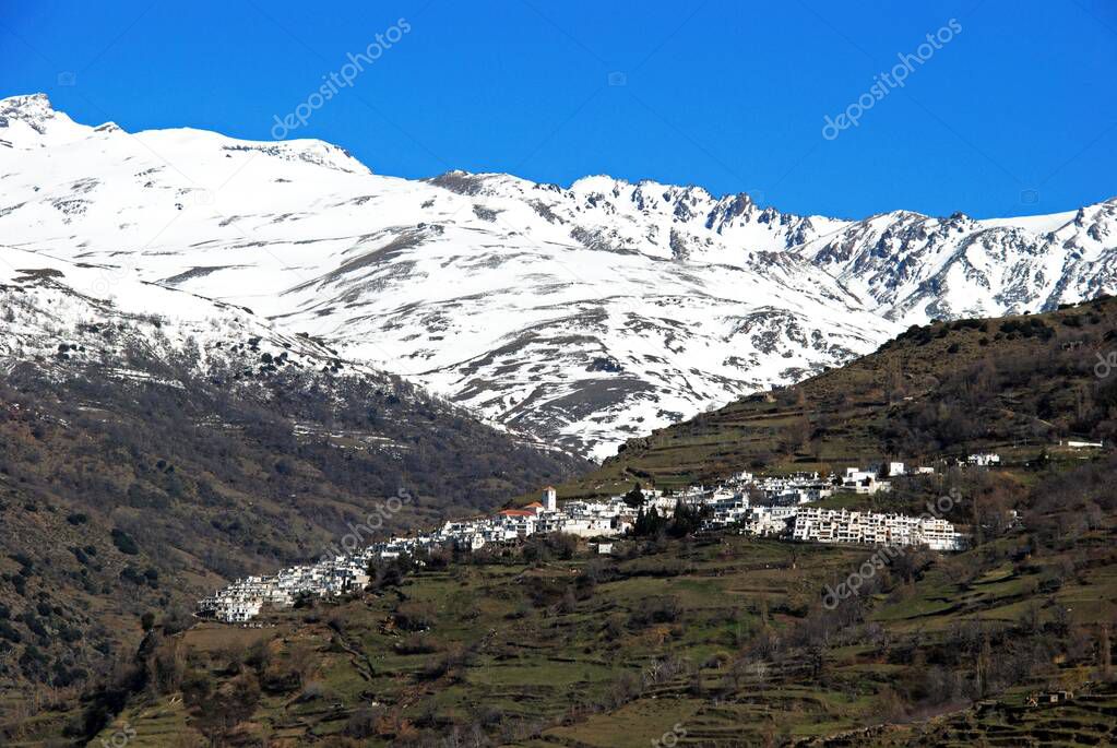 View of the town looking towards the snow capped mountains of the Sierra Nevada, Pampaneira, Las Alpujarras, Granada Province, Andalucia, Spain.