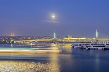 Eminonu, İstanbul, 13 Kasım 2019 İstanbul, Asya ve Avrupa kıtaları arasında rüya şehri. İstanbul 'dan manzara ve şehir manzarası ile metro köprüsü, gezi tekneleri, sabah erken saatlerde dolunay.