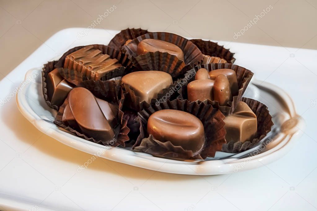 close up special chocolates with different figures in white plate on white background.
