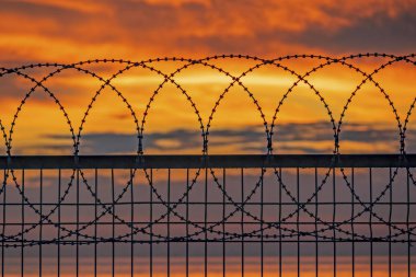 Gün batımı ve deniz kenarındaki çitler.