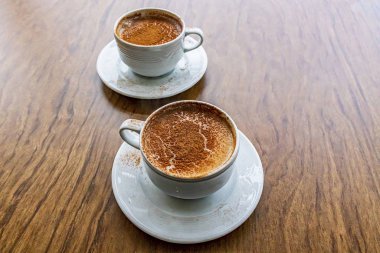 Geleneksel Türk sıcak içeceği sahlep veya kahverengi arka planda beyaz bardakta salep.