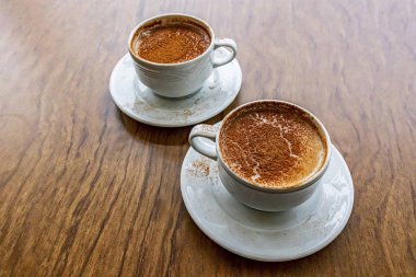 Geleneksel Türk sıcak içeceği sahlep veya kahverengi arka planda beyaz bardakta salep.