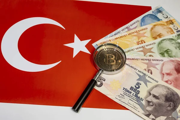Bitcoin madeni para ve büyüteçle arka planda Türk lira banknotlarını kapat