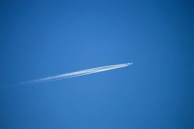 Uçağın gökyüzüne ve sol, uçak mavi gökyüzünde bulutlar küme ve küme bırakır bulutların içinde.