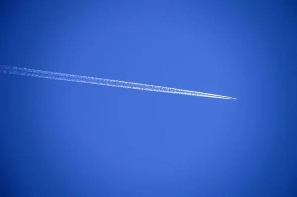 O avião no céu e o enxame de nuvens à esquerda, o plano no céu azul, e o enxame de nuvens que ele deixa . — Fotografia de Stock