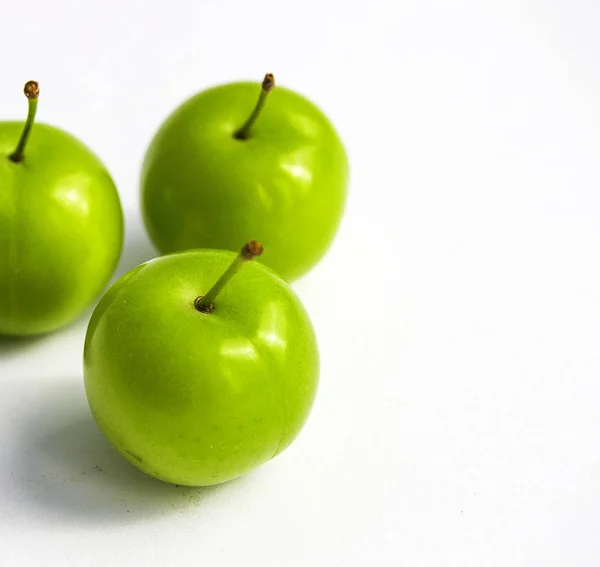 Prunes aigres sur fond blanc, prunes aigres merveilleuses, prunes vertes photos des premiers fruits en été — Photo