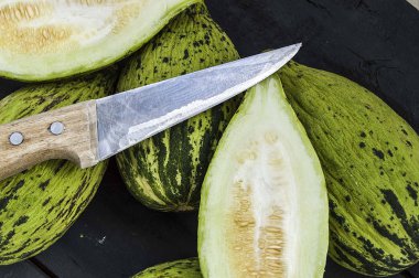 küçük kavun bir bıçak ile kesmek, olgunlaşmamış bir yemek kavun, olgunlaşmamış küçük kavun,