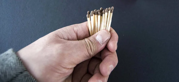 Man holding a matchstick, there are dozens of matchstick in one hand,