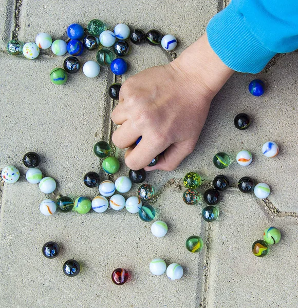 The children play with colored balls, played games in the street,child collecting colored balls, colored colored glass balls,