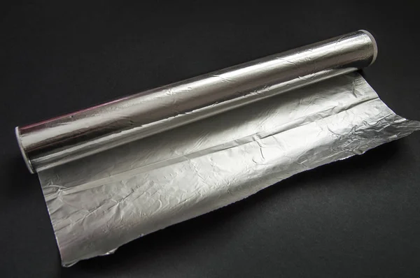 Mutfakta yemek için kullanılan alüminyum folyo siyah zemin üzerinde duruyor.