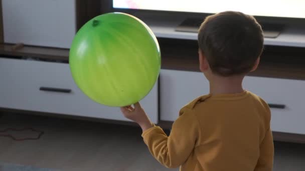 小男孩想给气球充气 气球和孩子 一个孩子 男孩和气球 手里拿着气球看电视 — 图库视频影像