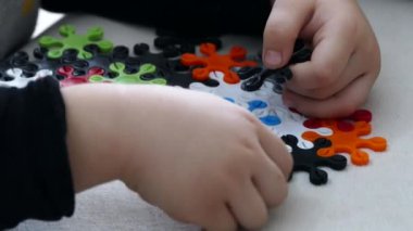 Renkli yapboz parçaları, bir çocuk tangramla şekillendirilmiş işler yapıyor.,