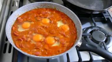 Sosisli yumurta, yumurta ve sosis pişirirken tavada pişiyor.,