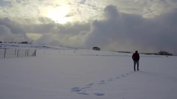 雪の上を歩く人とワイヤーメッシュバリア — ストック動画