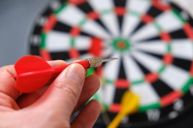 Yeşil dart, dart tahtası ve okla nişan alan bir adamın ellerinde okuyun.,