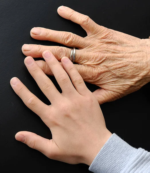 old woman's hand and young man touching her mercifully,old human and young human hand side by side, hand comparison,