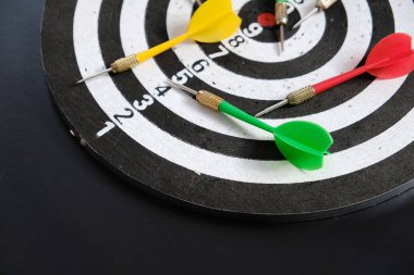 Yeşil dart, dart tahtası ve okla nişan alan bir adamın ellerinde okuyun.,