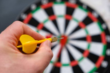 Yeşil dart, dart tahtası ve okla nişan alan bir adamın ellerinde okuyun.,