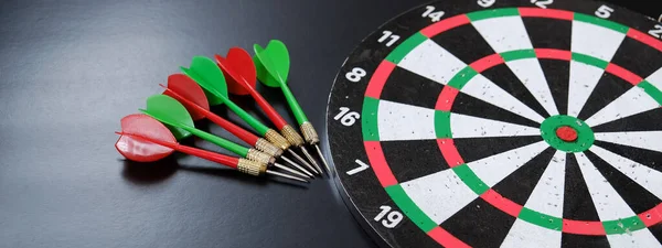 red, yellow, green dart arrows and dartboard, on black background