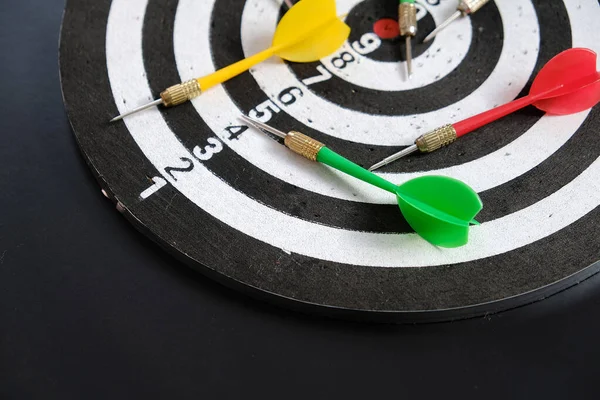 Yeşil dart, dart tahtası ve okla nişan alan bir adamın ellerinde okuyun.,