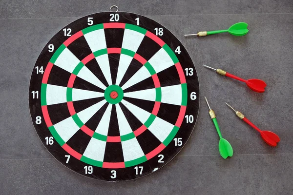 dartboard and dart arrows standing on black groundbdart arrow stuck and dart board,