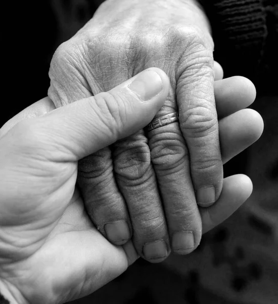 Młody Człowiek Delikatnie Trzyma Rękę Osoby Starsze — Zdjęcie stockowe