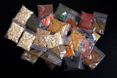 Siyah arka planda çeşitli organik GDO olmayan tohumlarla paketlenmiş.,