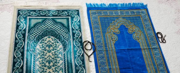 Islamic symbols, blue and green prayer rugs on a carpet in a house,