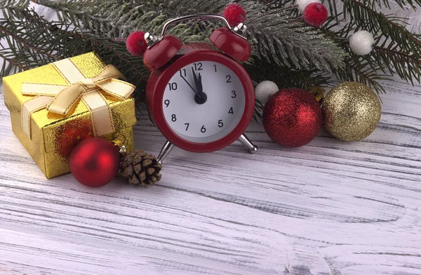Beyaz ahşap zemin üzerinde altın top Noel dekorasyonu ile hediye kutu kırmızı çalar saat koni doğal çam dalları — Stok fotoğraf