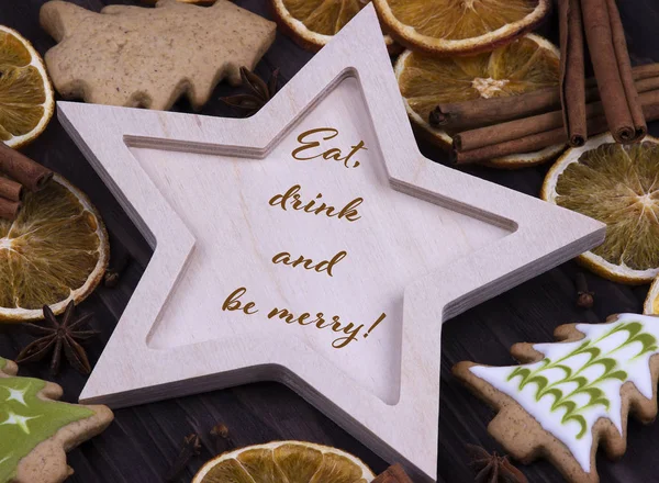 Navidad Navidad Año Nuevo Tarjeta de felicitación navideña con estrella de madera estrella de canela anice naranjas secas Galletas de árbol de Navidad y texto Come bebida y sé feliz — Foto de Stock