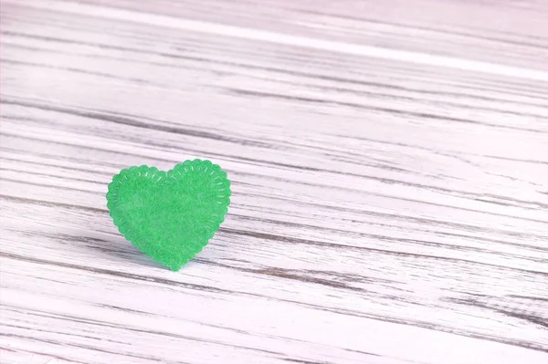 Green heart of felt on a white gray wooden background. Valentine Day.Greeting card.Wedding,