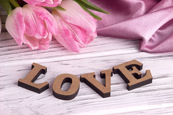 バレンタインの日にエレガントな木製白地にチューリップの花のピンク生地とレタリング愛サインある静物 — ストック写真