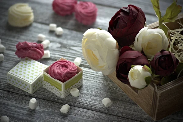 Червоно-білі квіти масляної чашки біло-рожеві зефірні зефіри з маленькою картонною коробкою на сірому дерев'яному фоні. Копіювати простір . — стокове фото