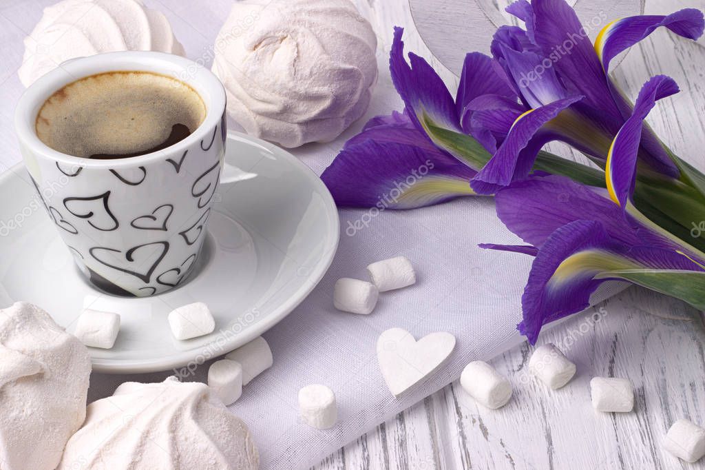 Still life with cup of coffe marshmallow zephyr iris flowers heart sign on white wooden background. Wedding. Valentines Day. Womans Day. 8 march