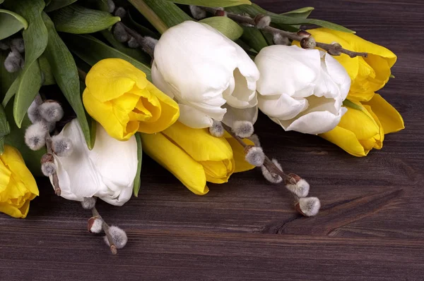 Красиві жовті та білі тюльпани з весняними гілками та бутонами на коричневому дерев'яному фоні — стокове фото