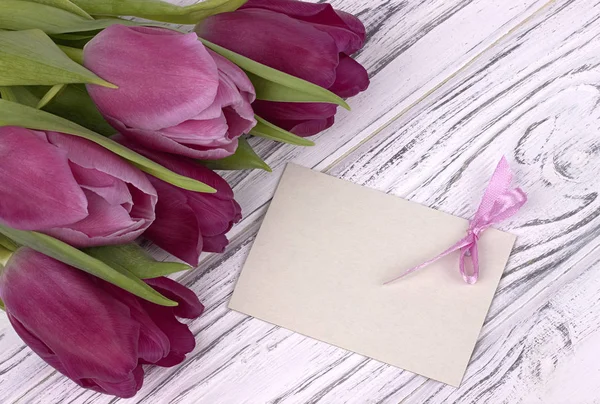 Tulipanes morados con papel blanco sobre fondo blanco de madera con tarjeta de texto. Día de la Mujer. 8 de marzo. Día de la Madre . — Foto de Stock